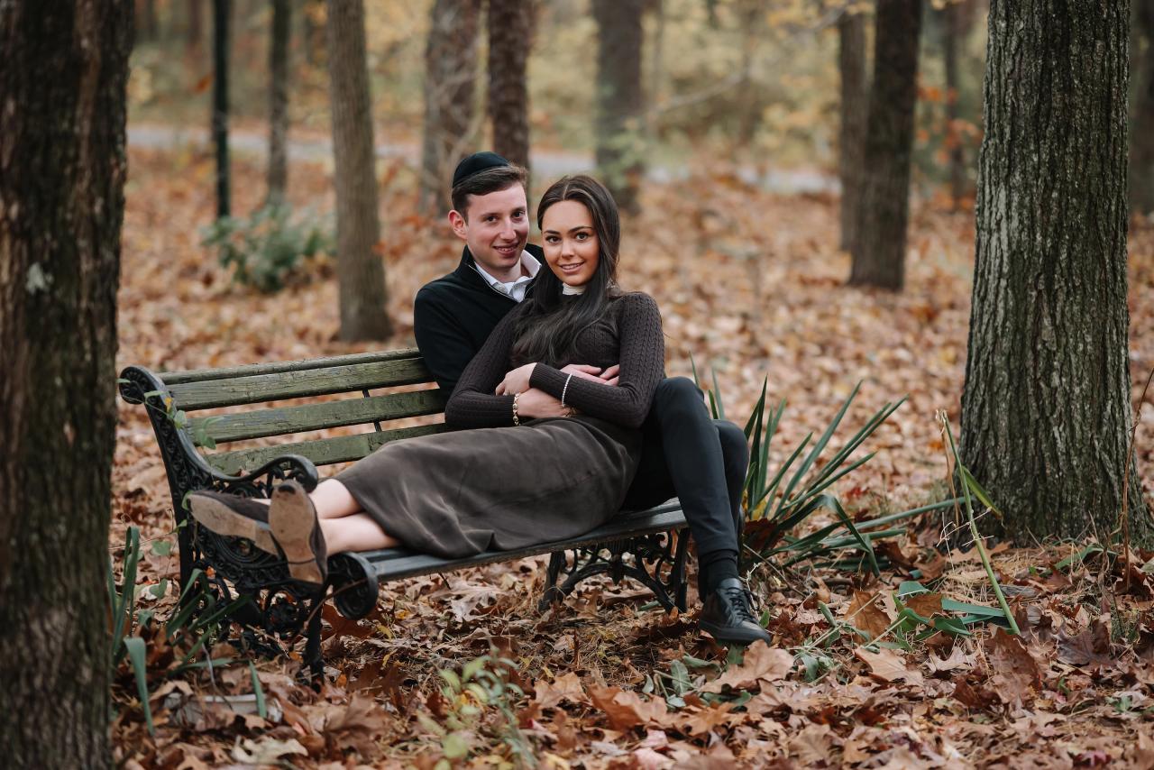 Couple relaxing together on a park bench surrounded by autumn trees