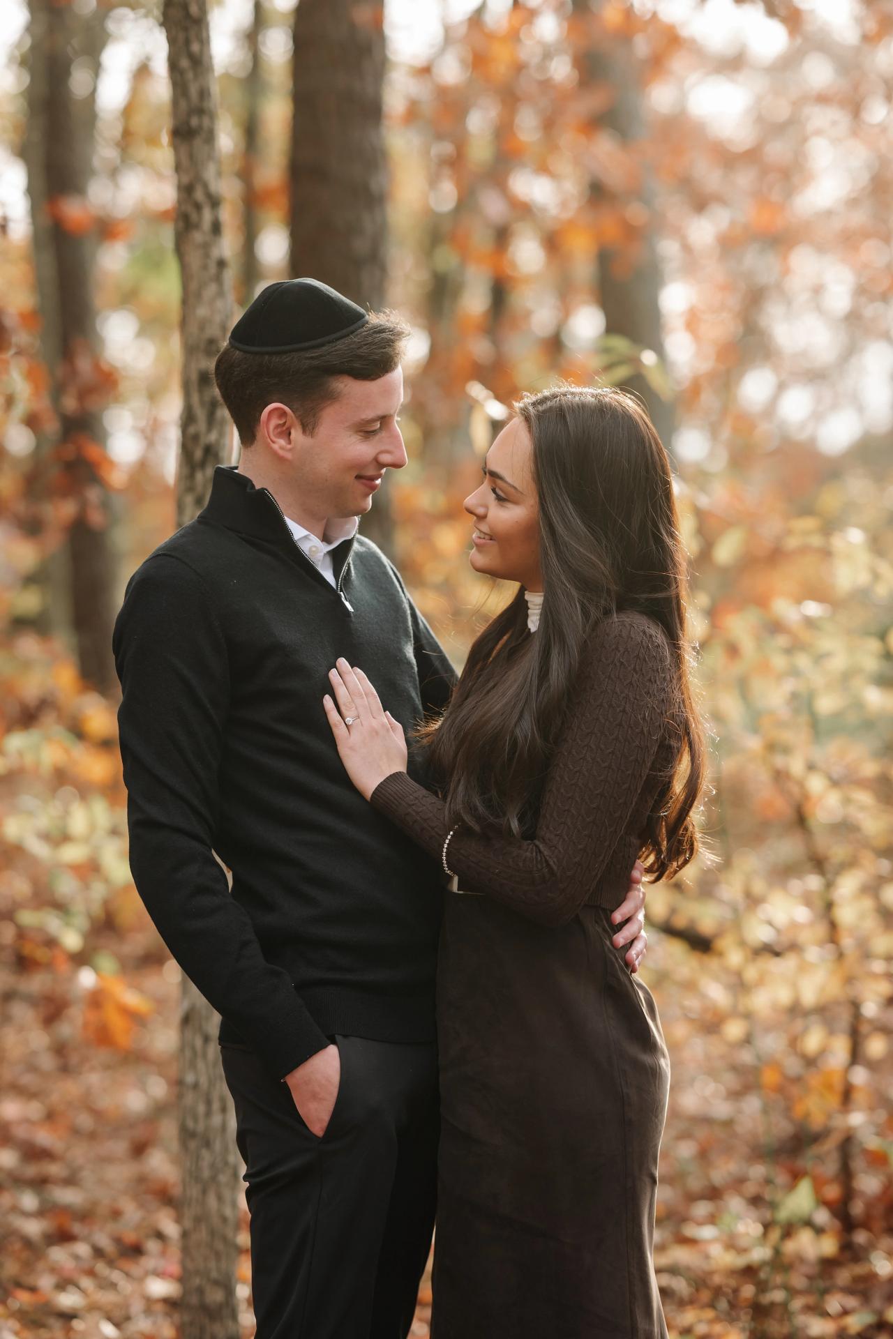 Couple smiling at each other among tall autumn trees