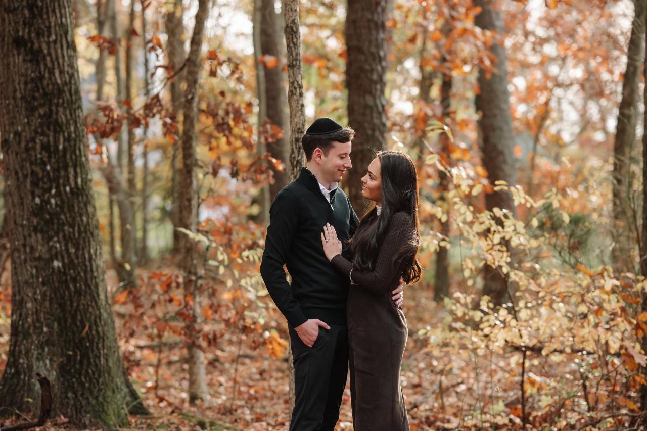 Wide portrait of a couple standing together on a woodland path