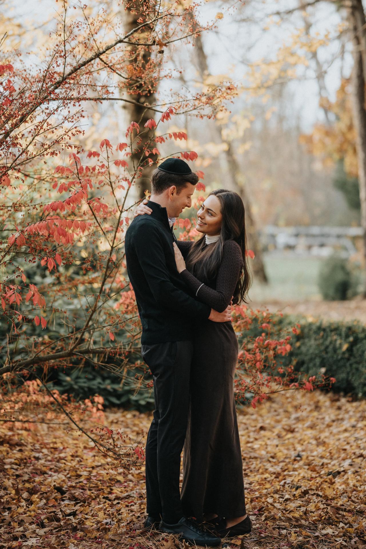 Couple facing each other on a leaf-covered woodland path