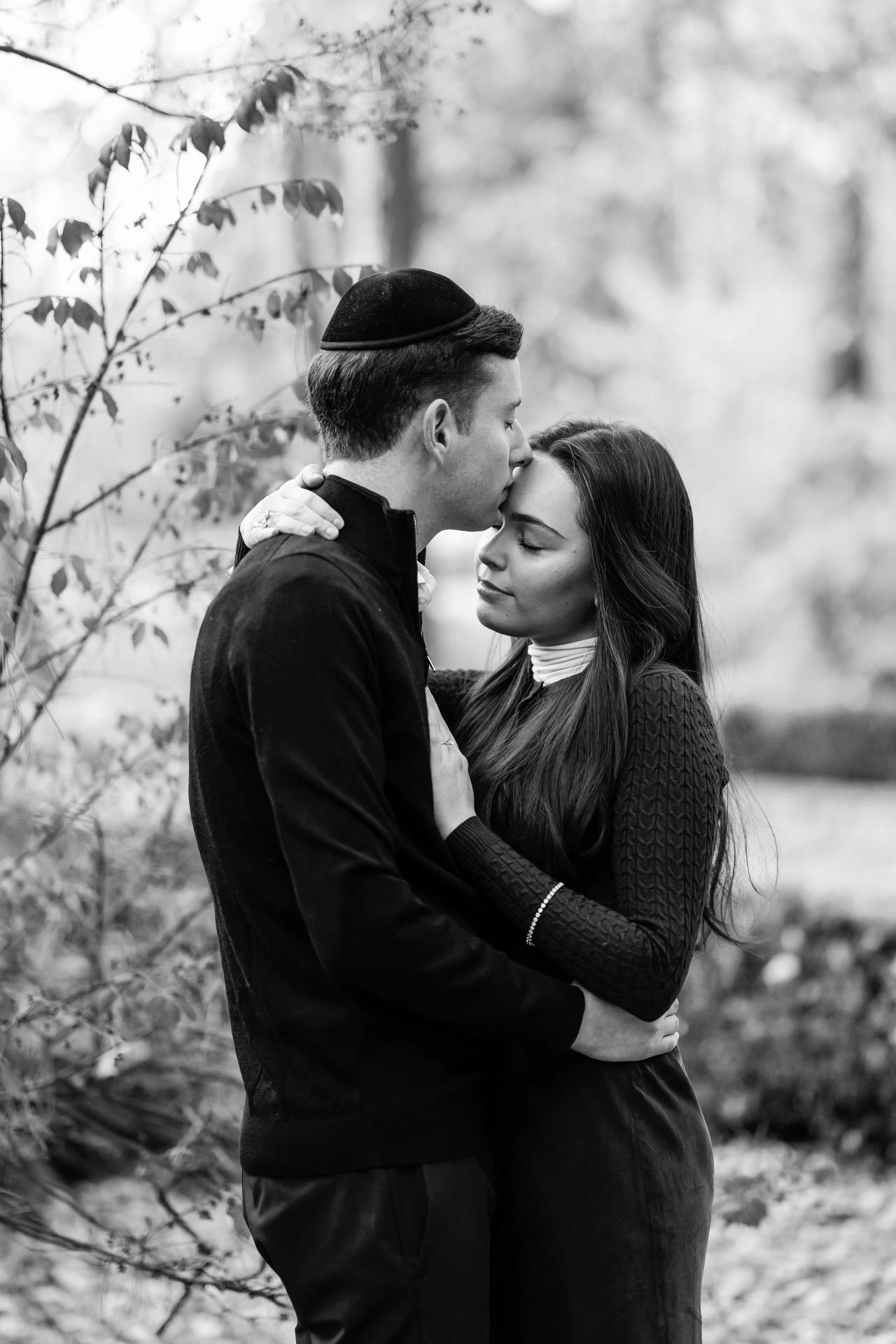 Black-and-white portrait of a couple sharing a quiet moment in the woods