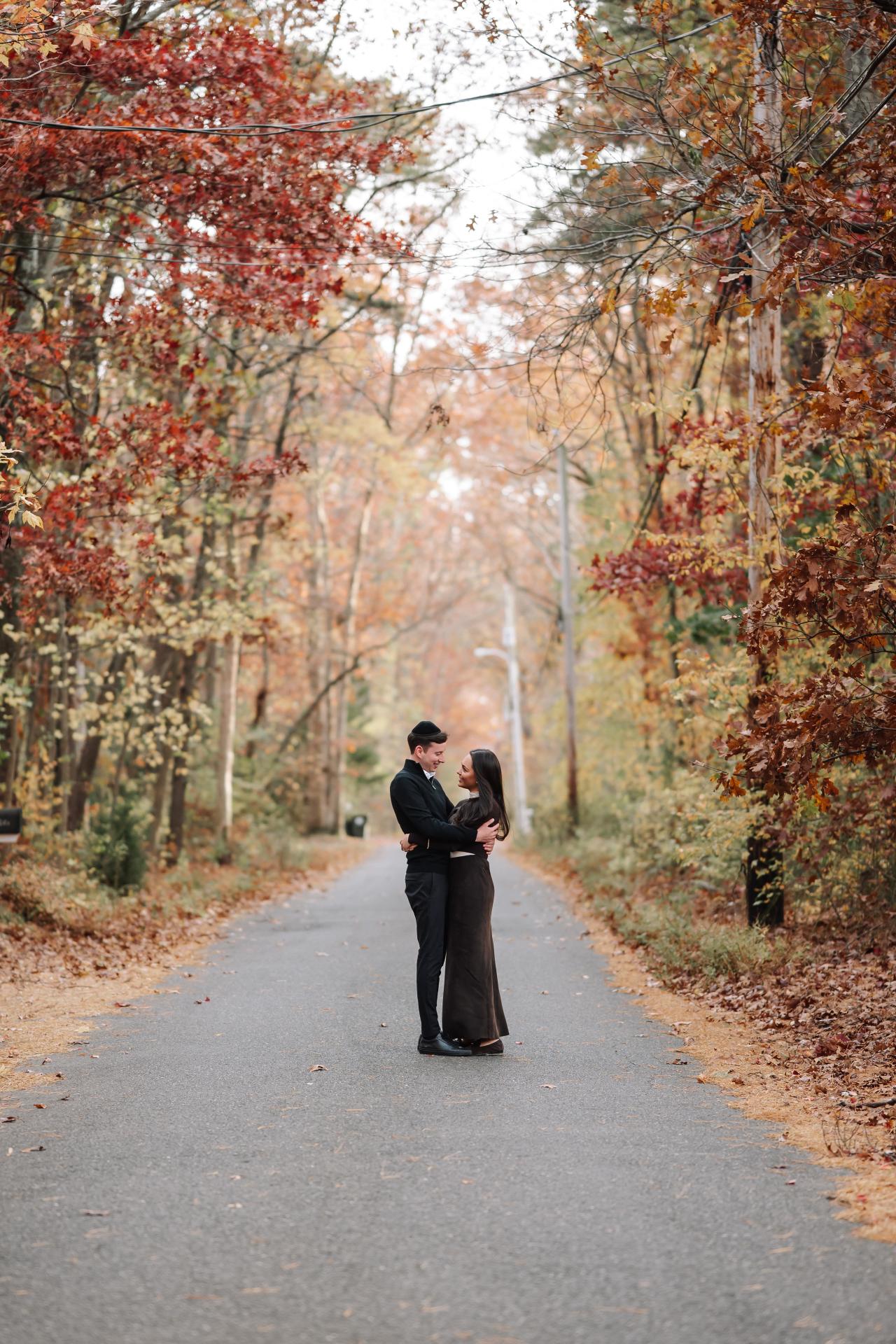 Couple embracing in the middle of an autumn tree-lined road
