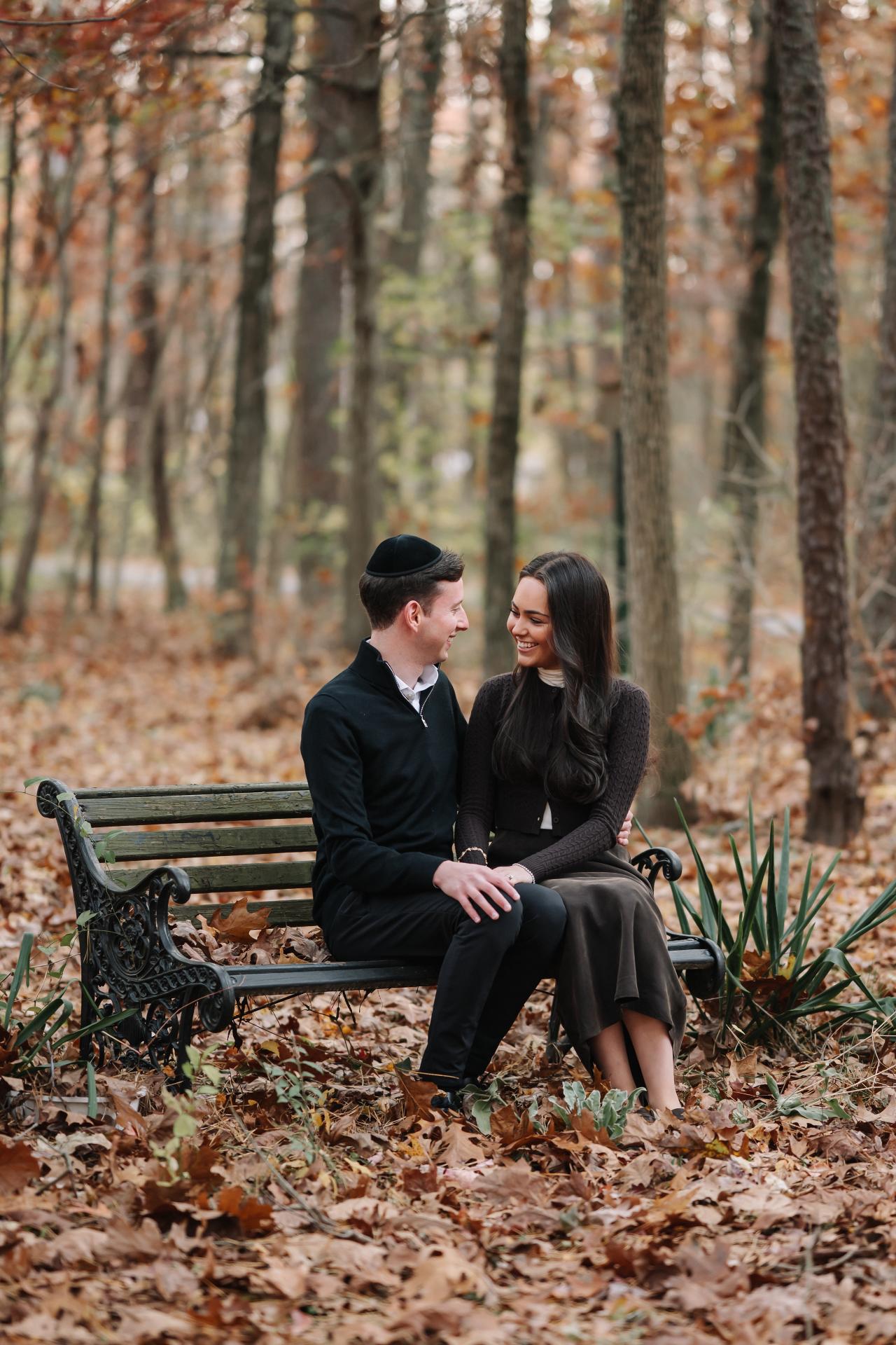 Couple laughing together while seated on a woodland park bench