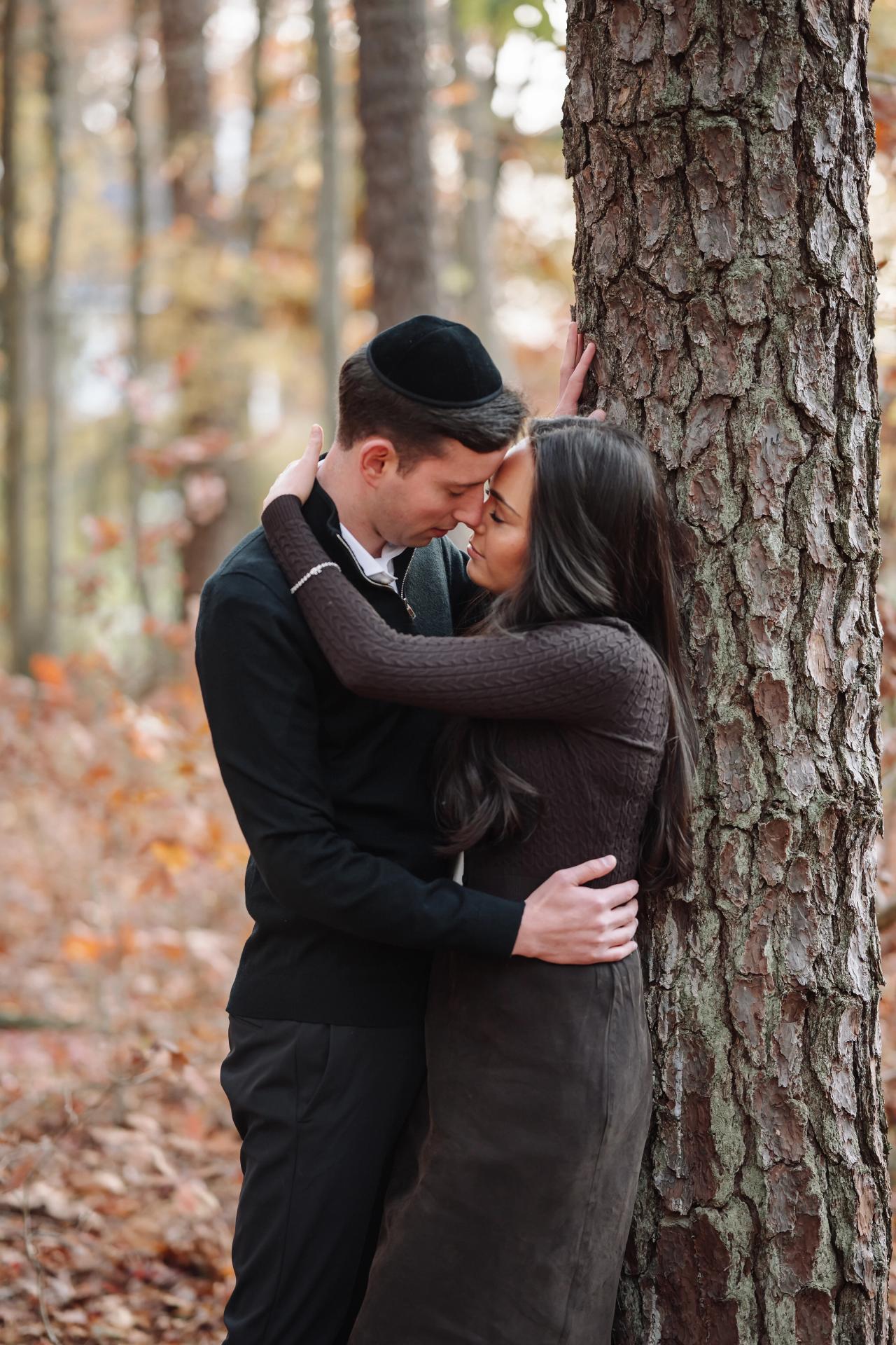 Couple embracing beside a tree during an outdoor autumn portrait session