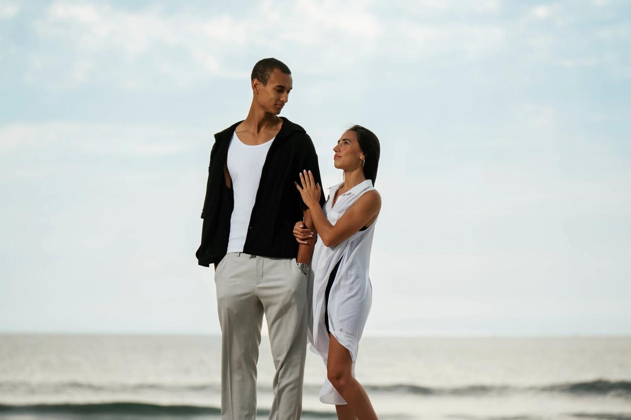 Couple sharing a smile beside the ocean before a beach proposal