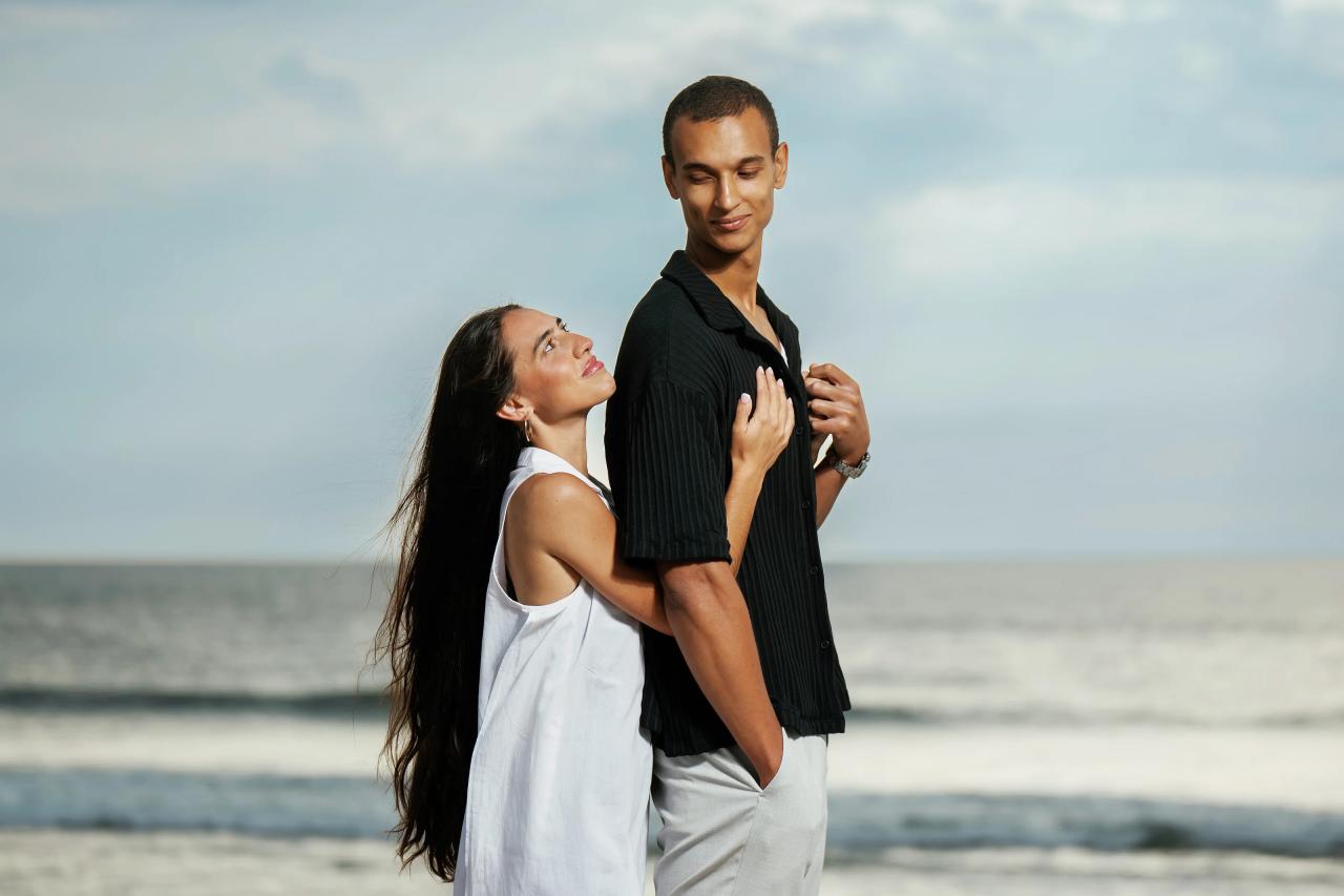 Woman laughing while embracing her partner beside the ocean