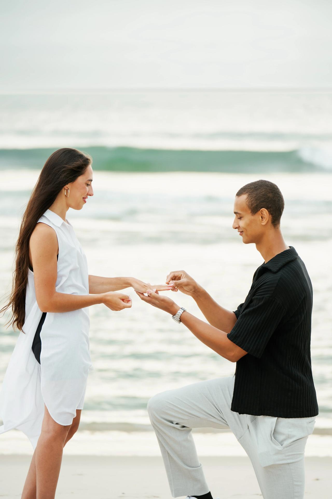 Close view of a man placing an engagement ring on his partner’s hand