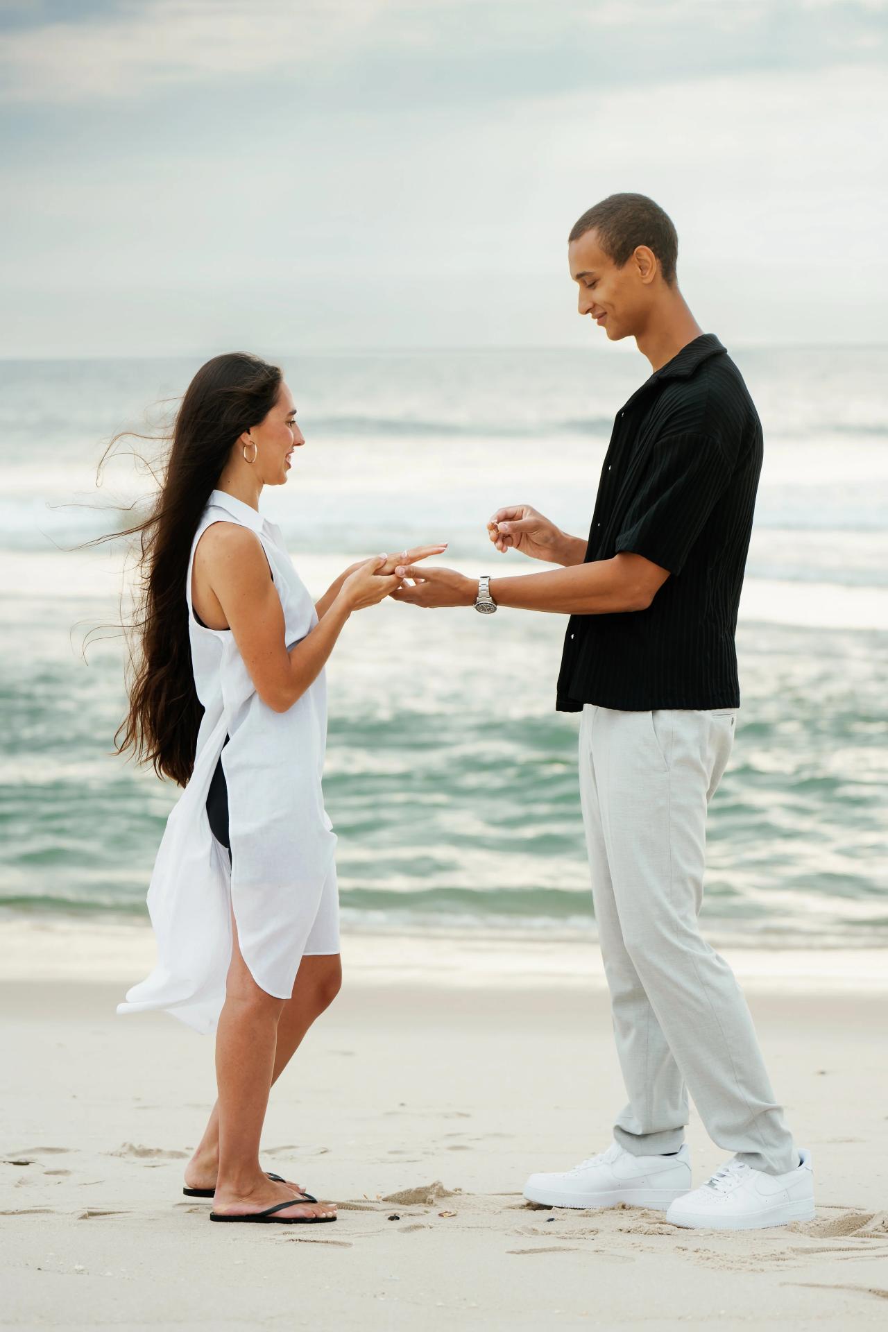 Couple holding hands and admiring the ring after their beach proposal