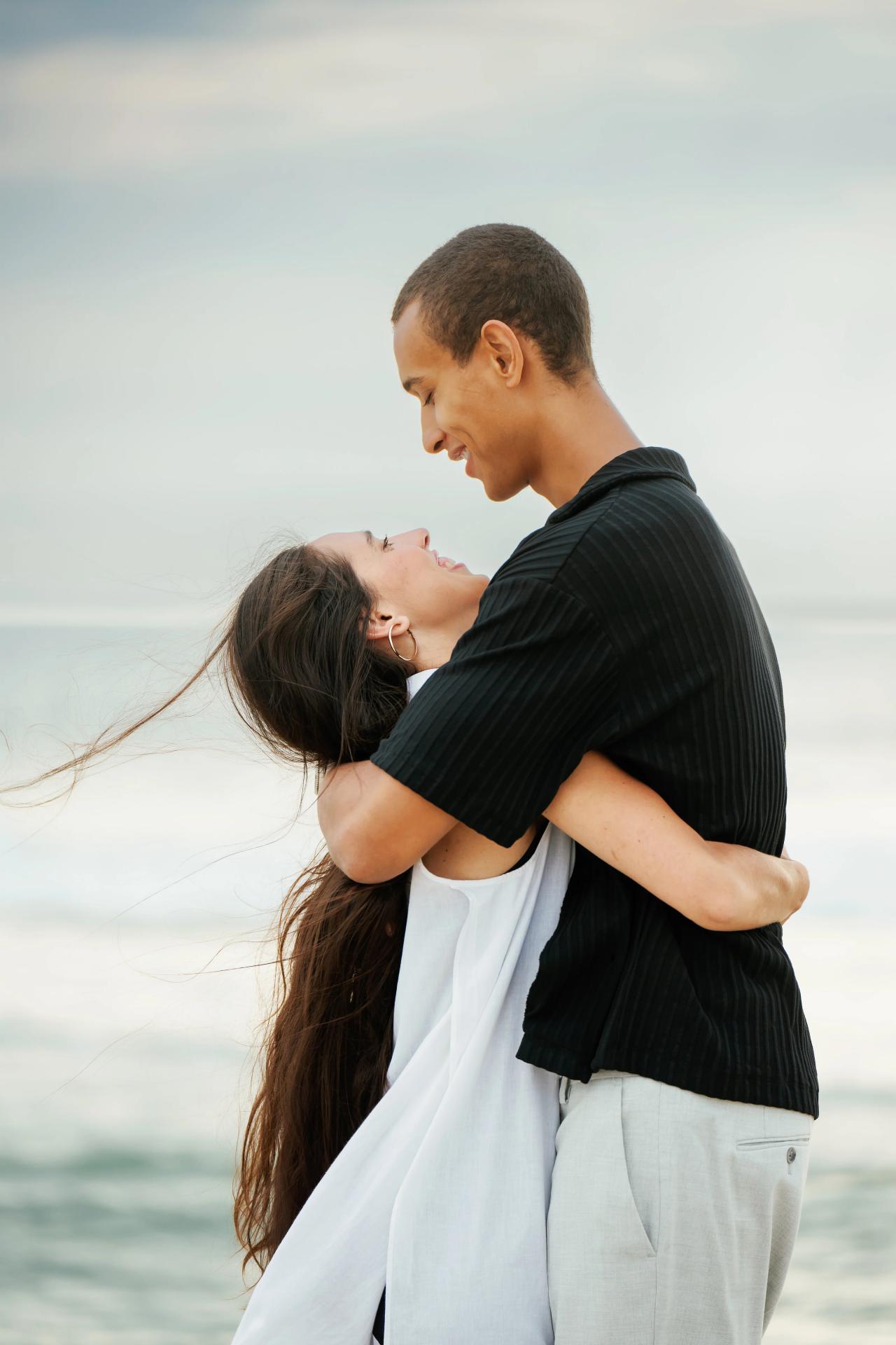 Close portrait of a couple embracing with the ocean behind them