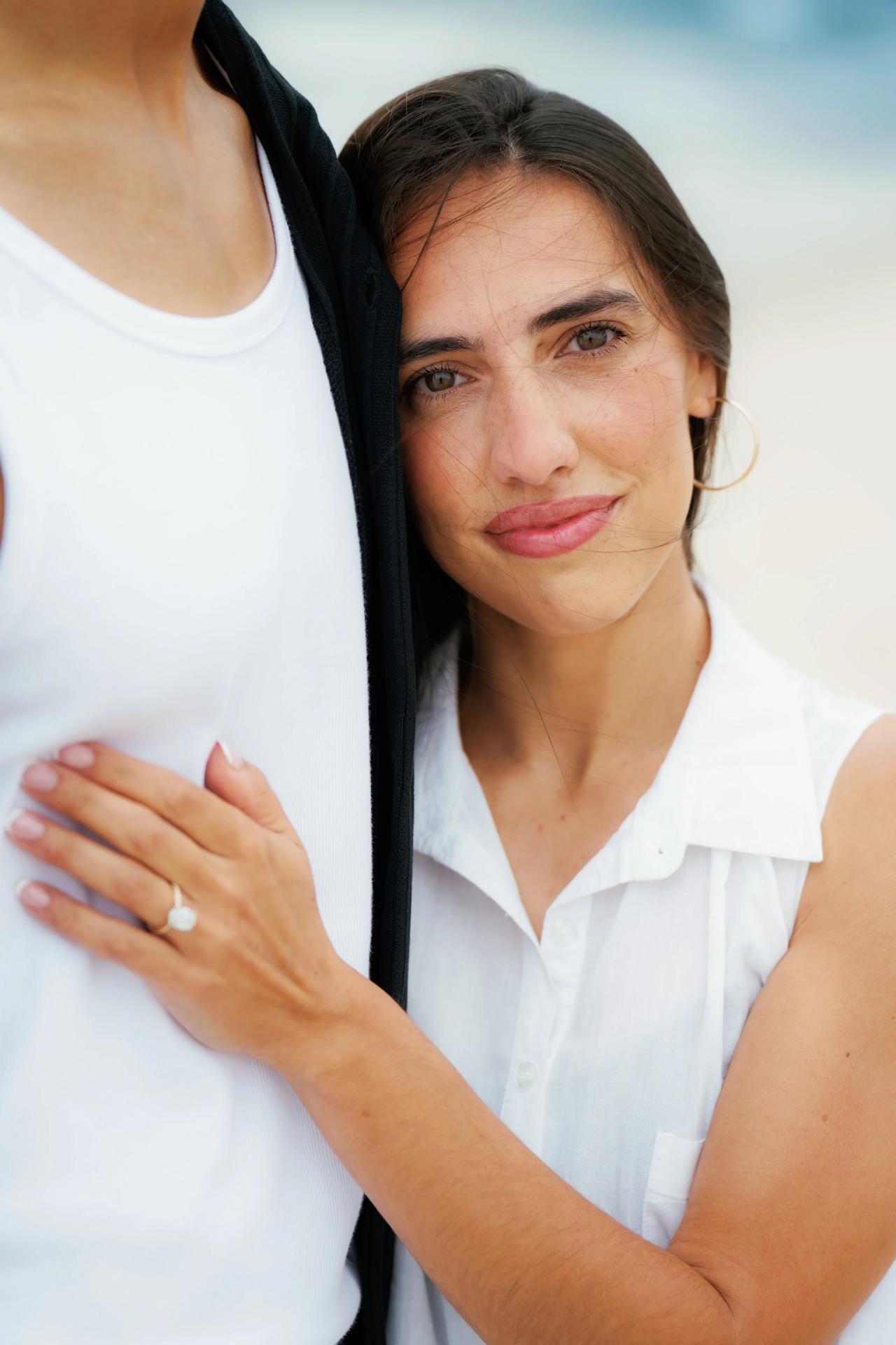 Close portrait of a woman leaning against her partner after their beach proposal