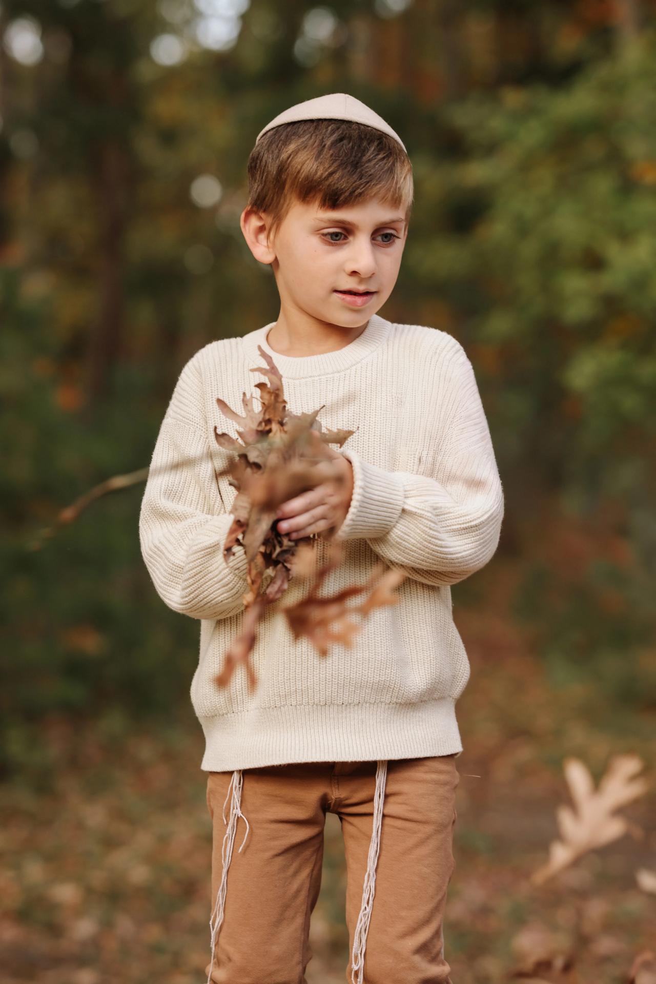 Young boy holding autumn leaves during a family photoshoot