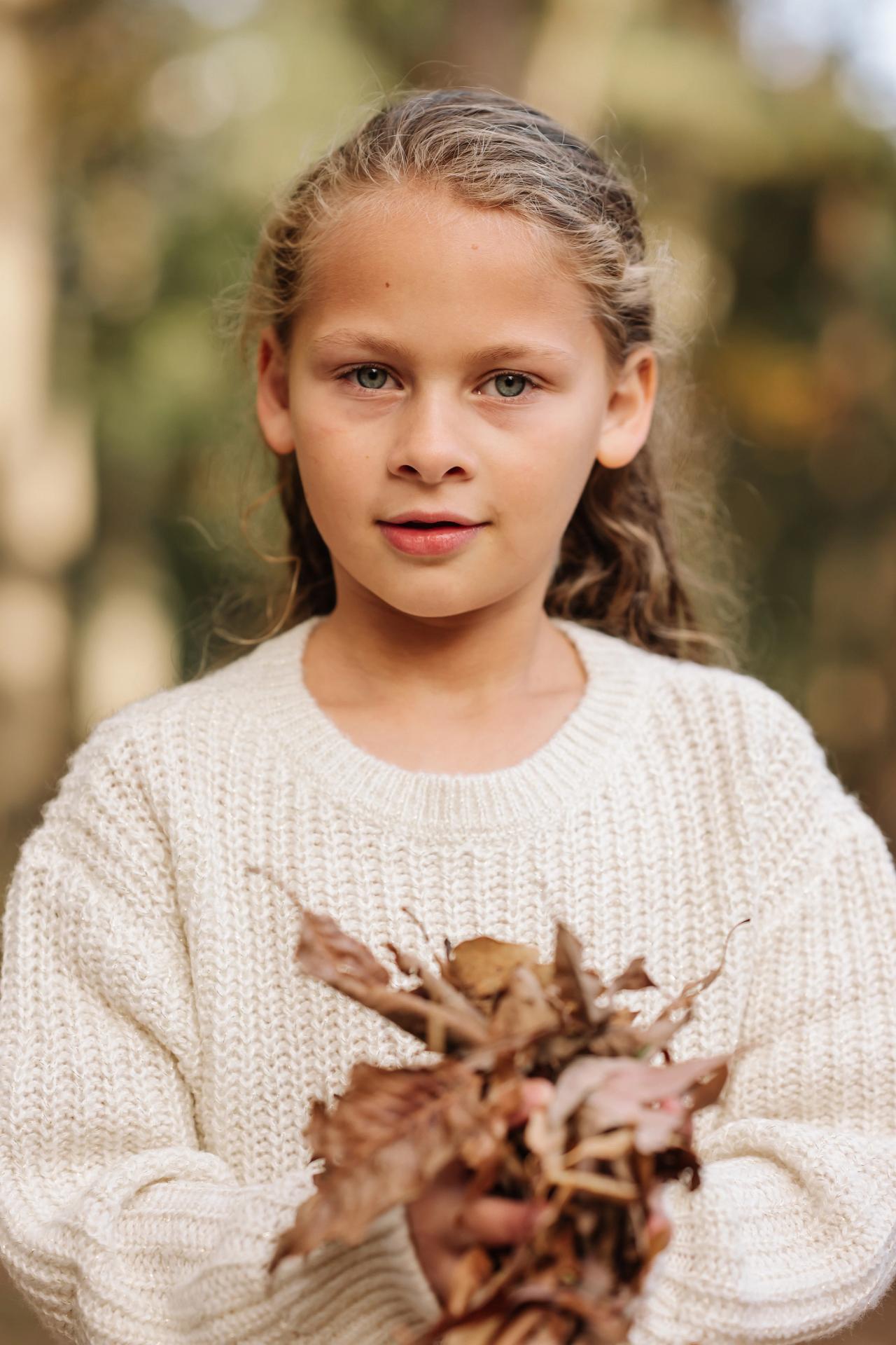 Girl holding colorful leaves in the autumn woods