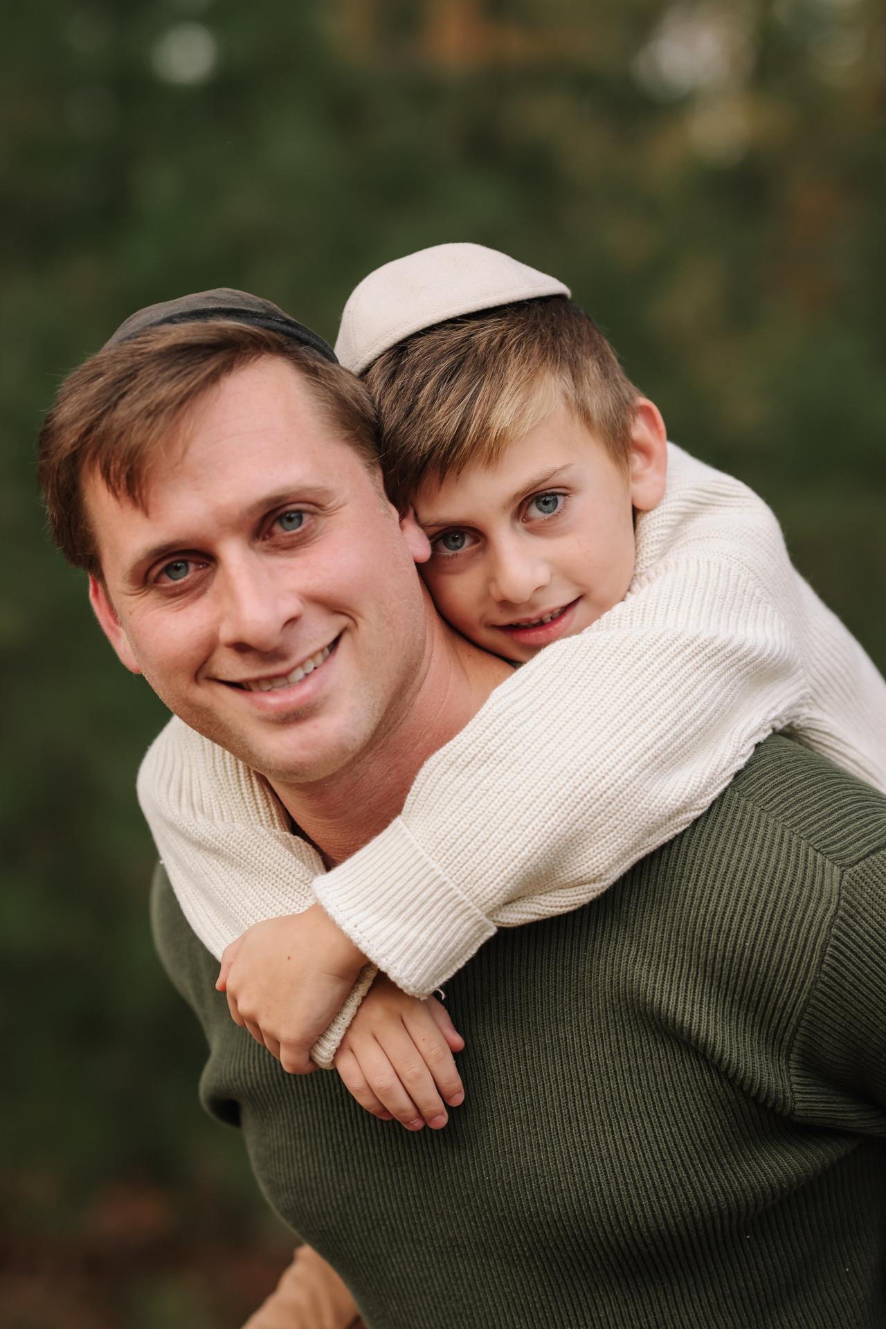 Father giving his son a piggyback ride during a woodland photoshoot