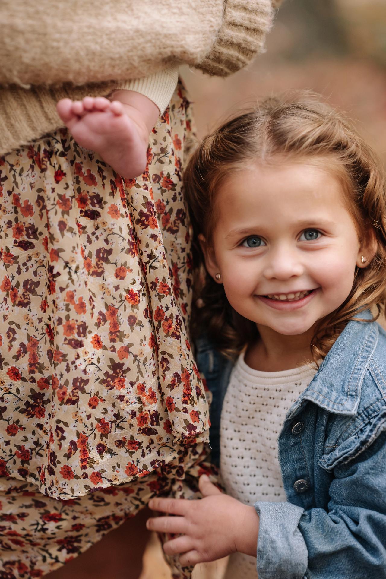 Young girl smiling up beside her mother in the autumn woods