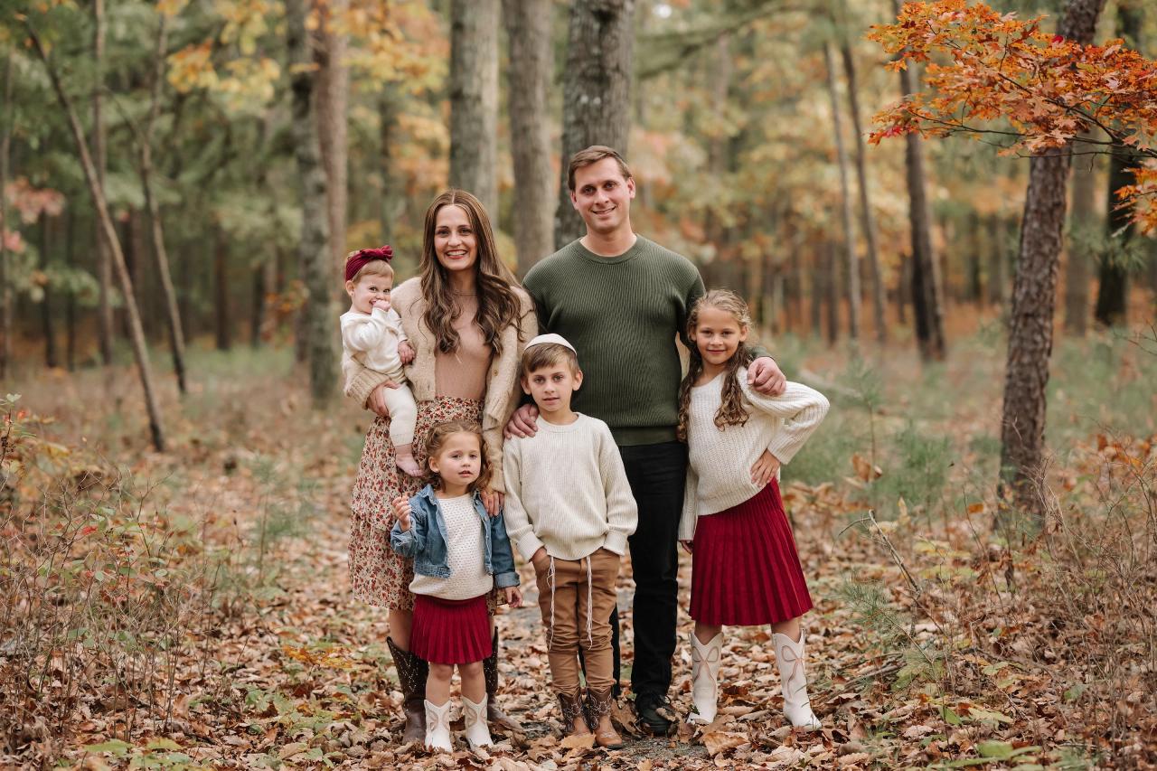 Parents and four children standing together on a woodland path