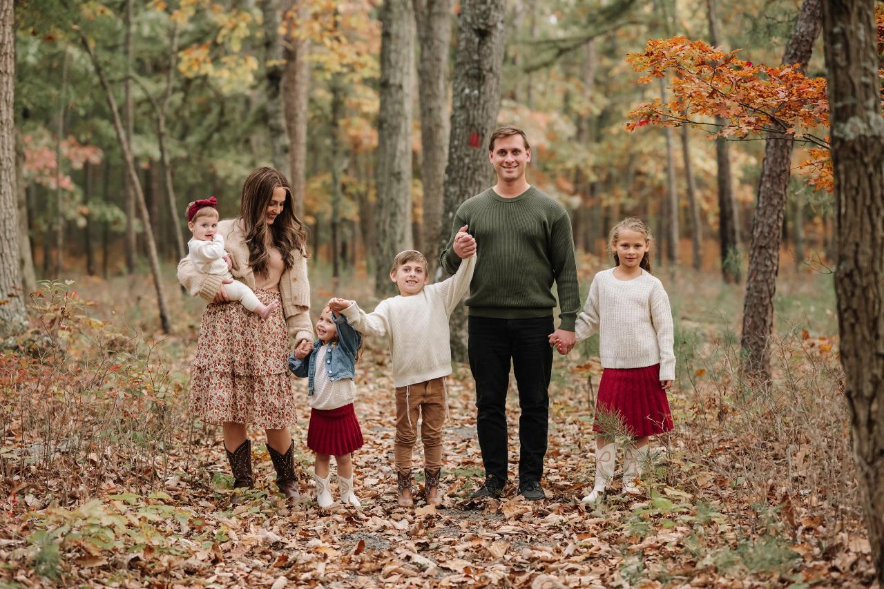 Family walking toward the camera along a leaf-covered path