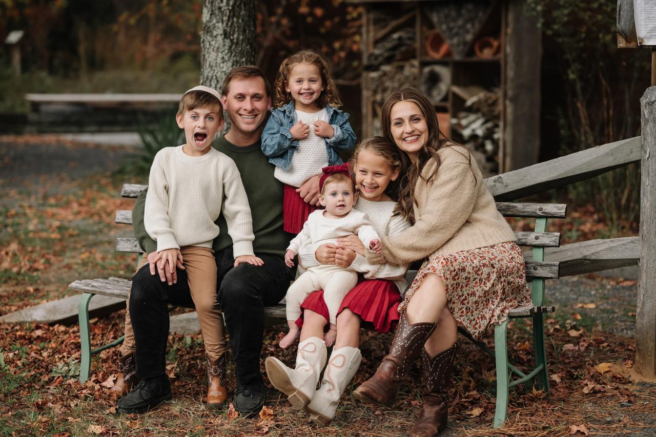 Family of six sitting together on a rustic woodland bench