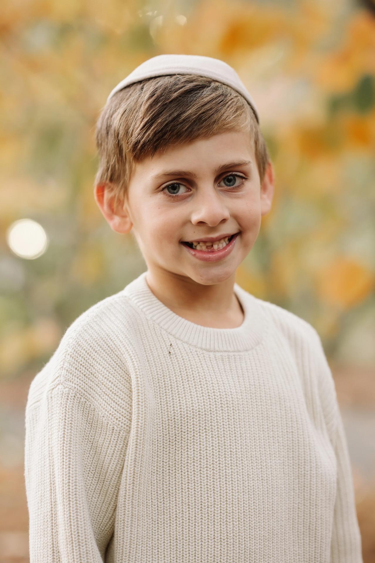 Boy smiling beside golden autumn foliage
