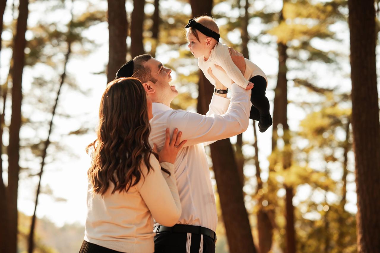 Father lifting his smiling baby while the mother looks on