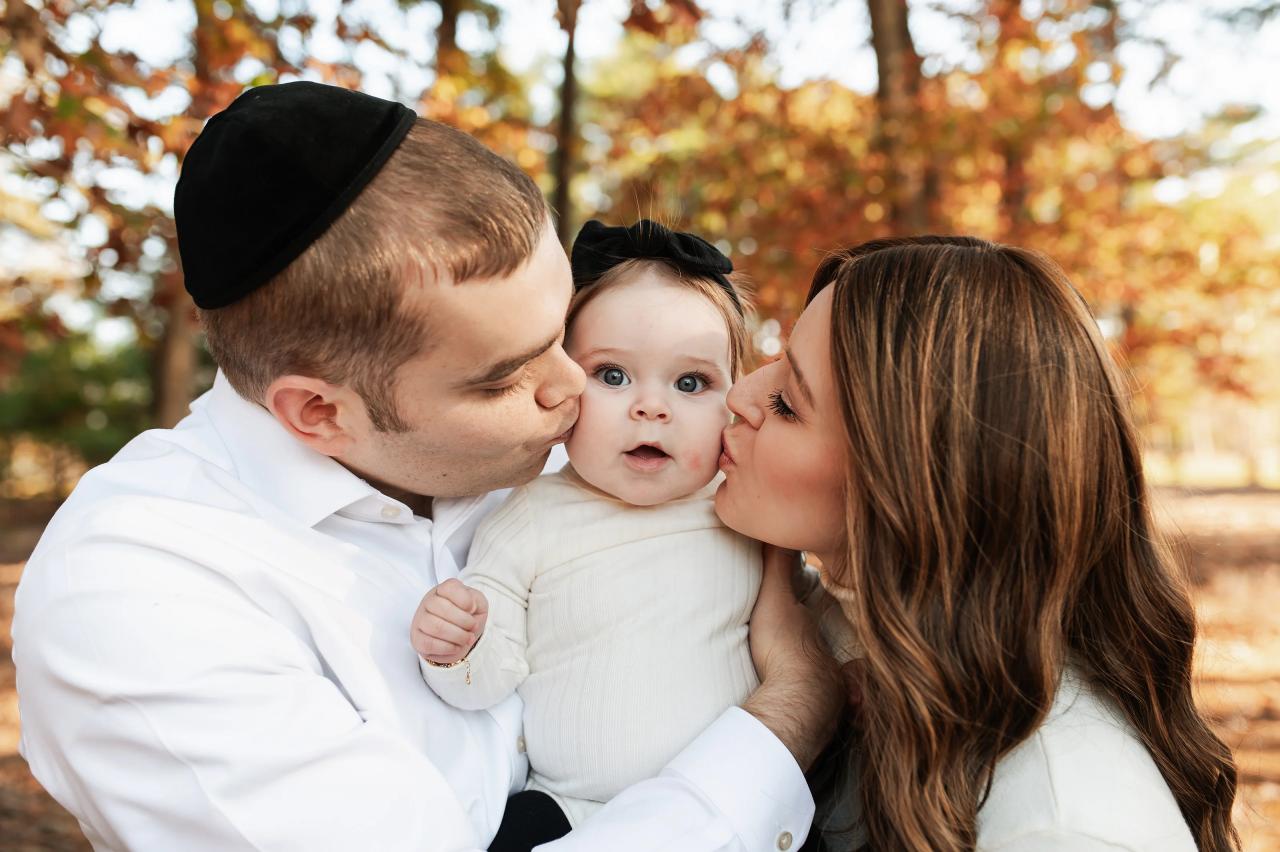 Parents kissing their baby during an outdoor family session