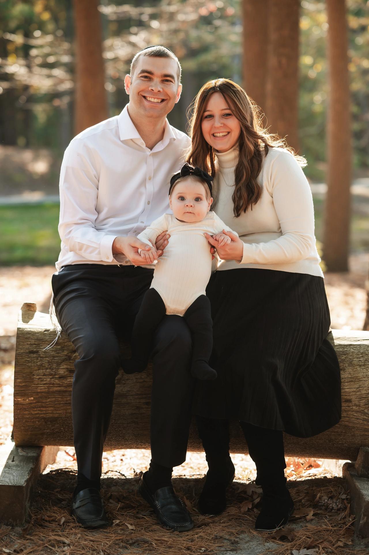 Family of three sitting together on a woodland bench