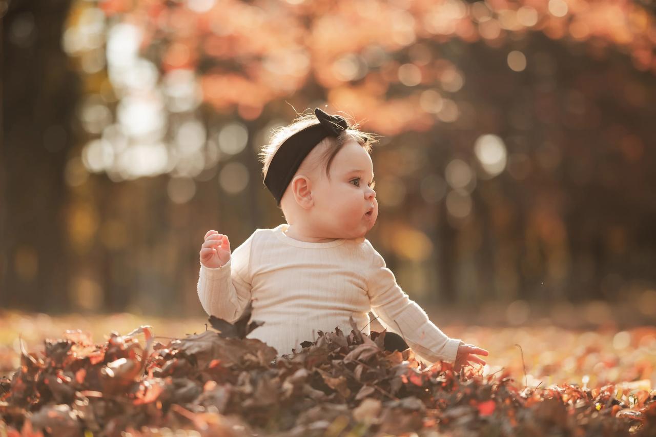 Baby sitting among colorful autumn leaves