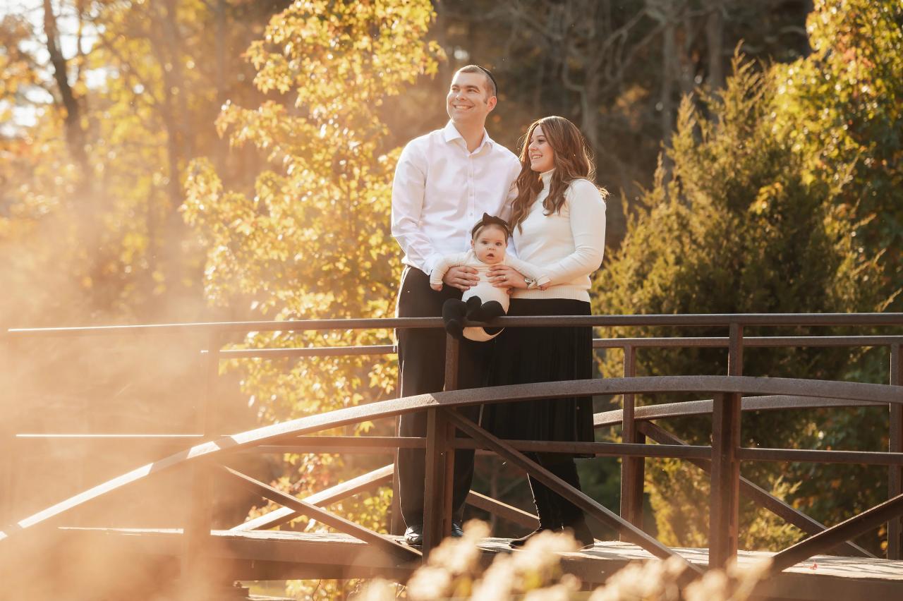 Family portrait on a wooden footbridge in warm autumn sunlight