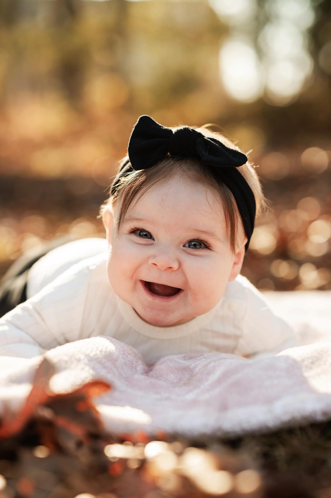 Baby smiling on a blanket surrounded by fallen leaves