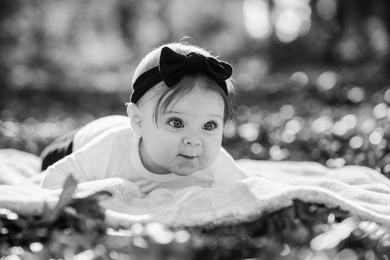 Black-and-white baby portrait on a blanket outdoors
