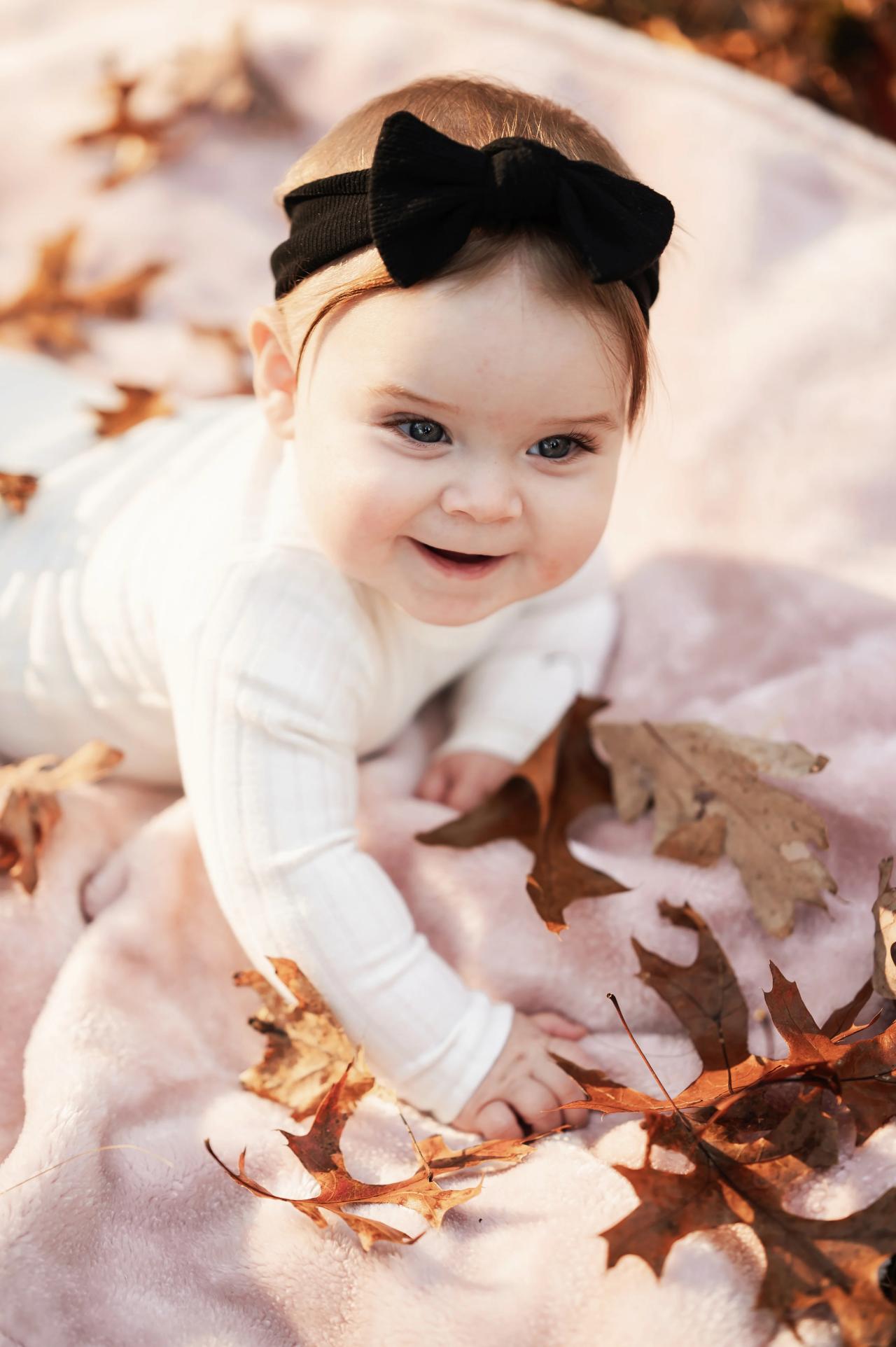 Baby laughing on a blanket among autumn leaves