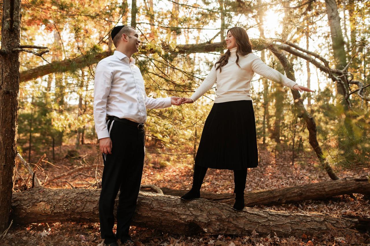 Couple holding hands beneath sunlit autumn trees