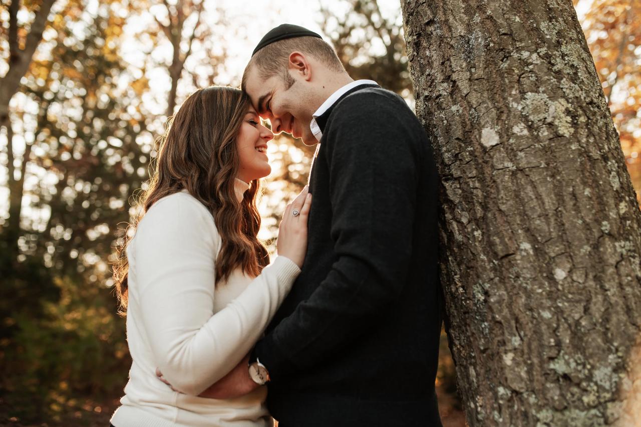 Parents leaning together beside a woodland tree