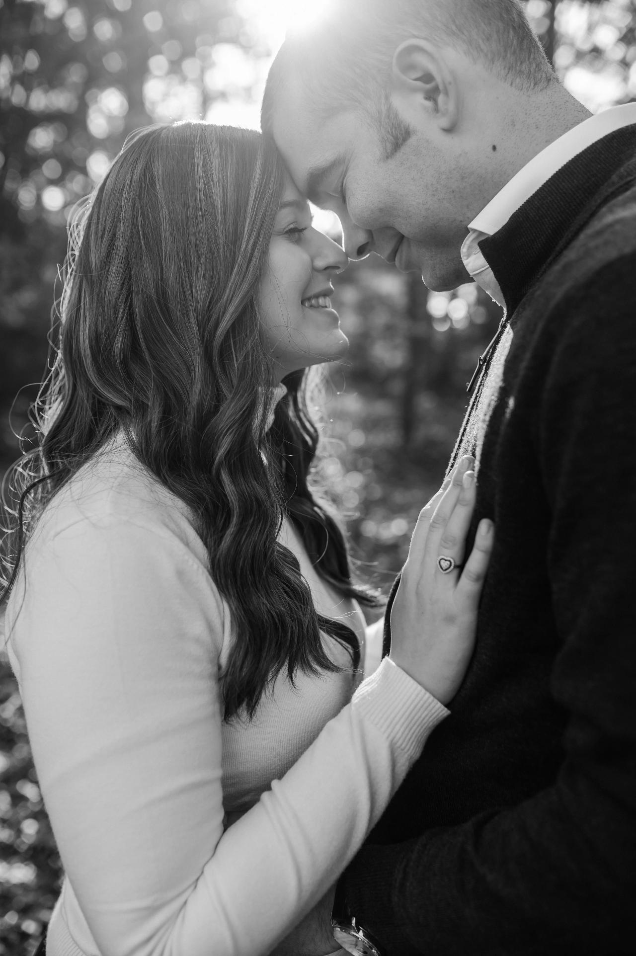 Black-and-white portrait of parents sharing a quiet moment in the woods