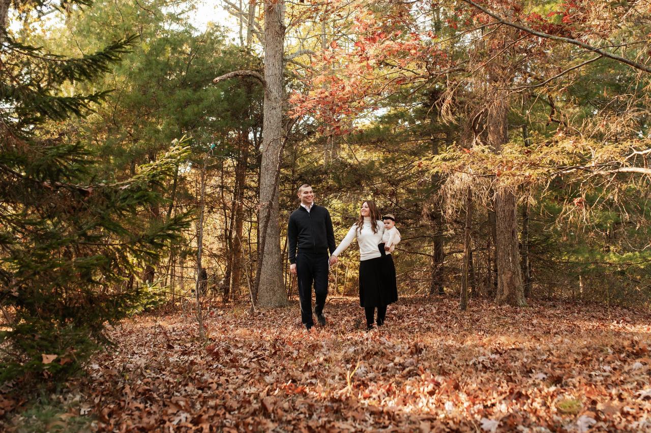 Parents walking together along a leaf-covered woodland path
