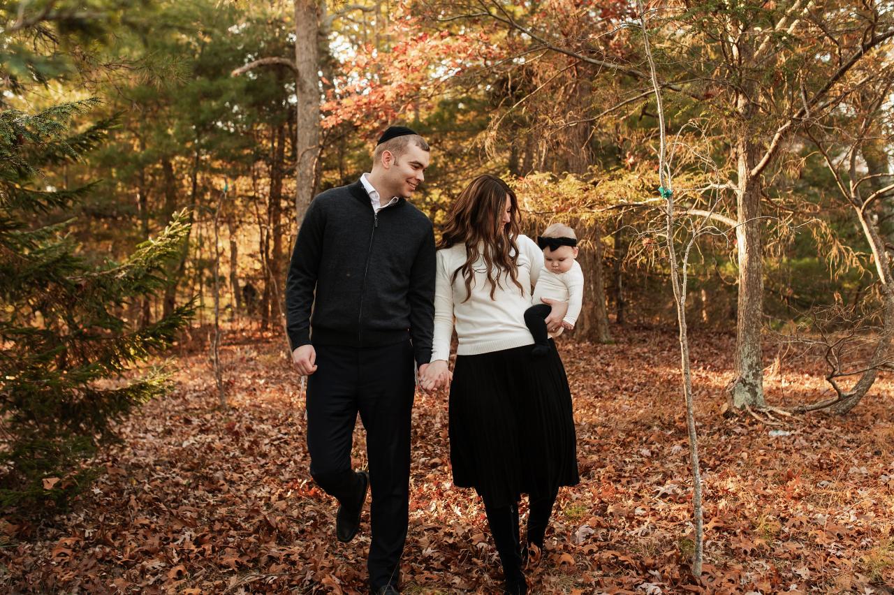 Family walking hand in hand through the woods with their baby