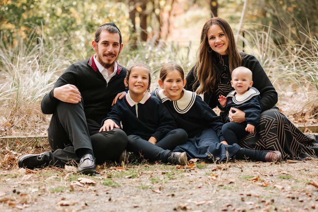 Family of five sitting together along a woodland path