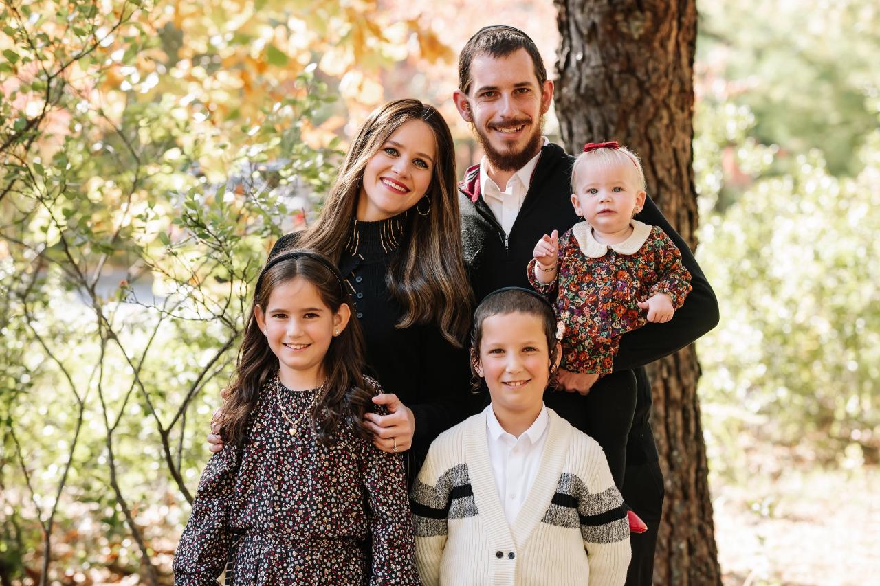 Parents and three children smiling beside a tree