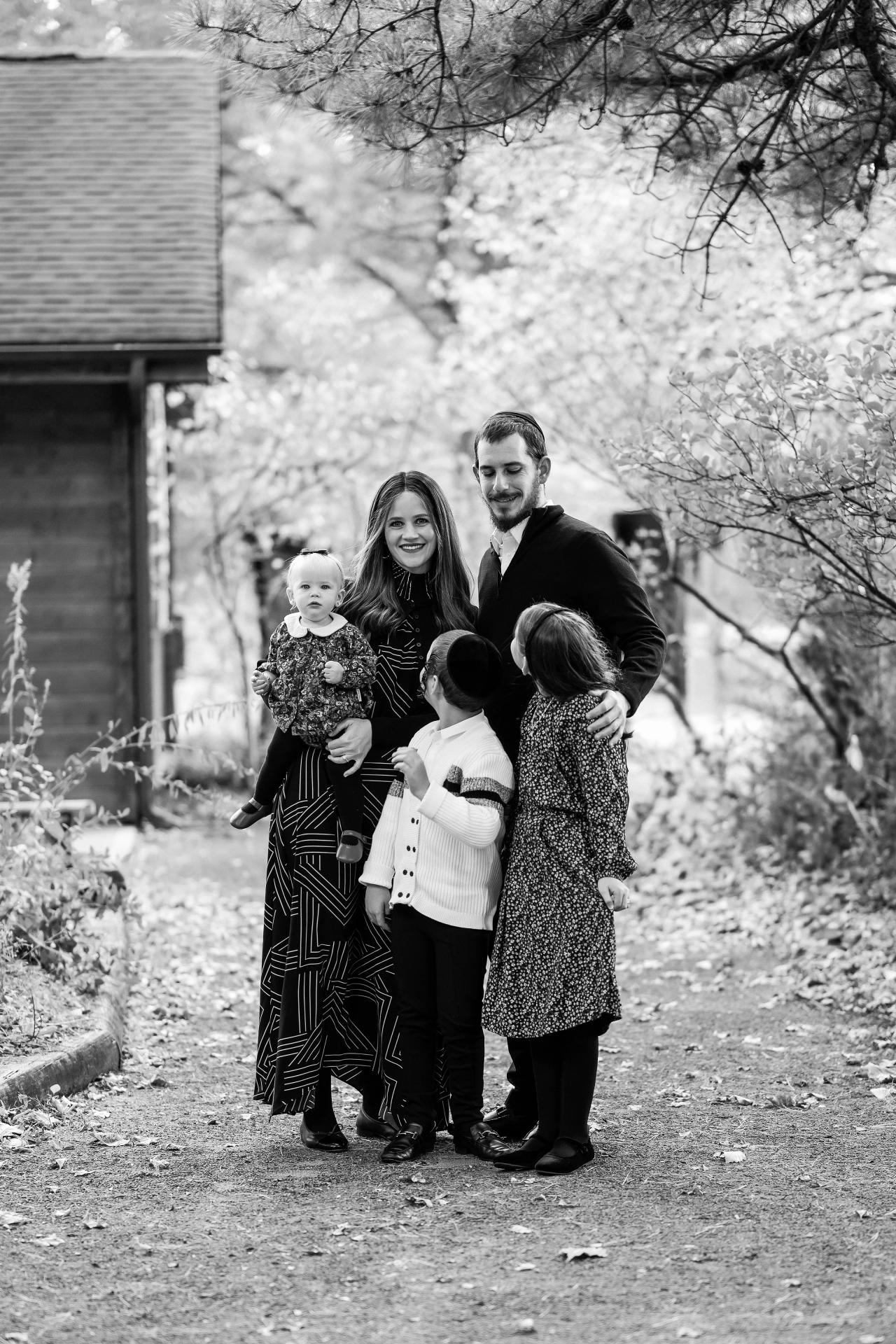 Black-and-white family portrait beside a rustic wooden cabin