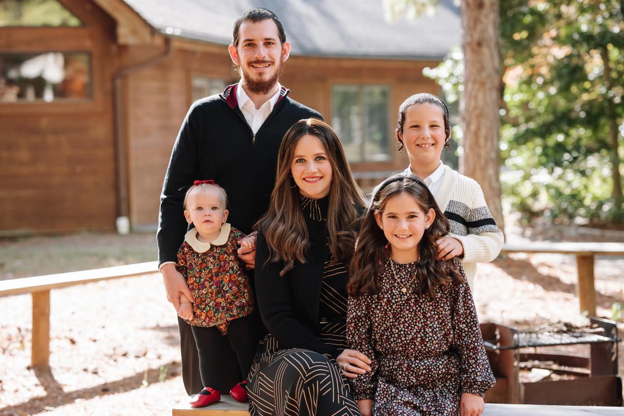 Family gathered on a bench in front of a wooden cabin