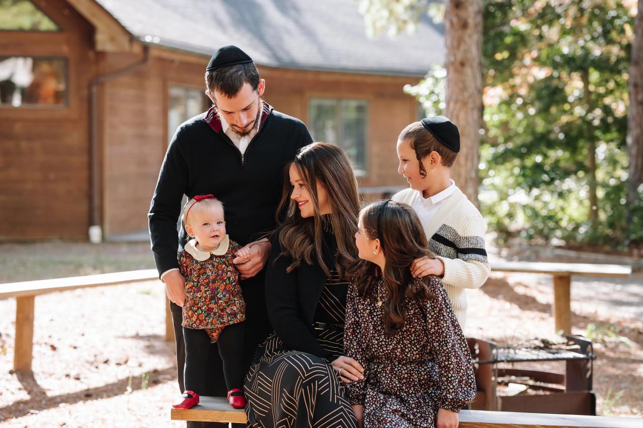 Parents sharing a candid moment with their children beside a cabin