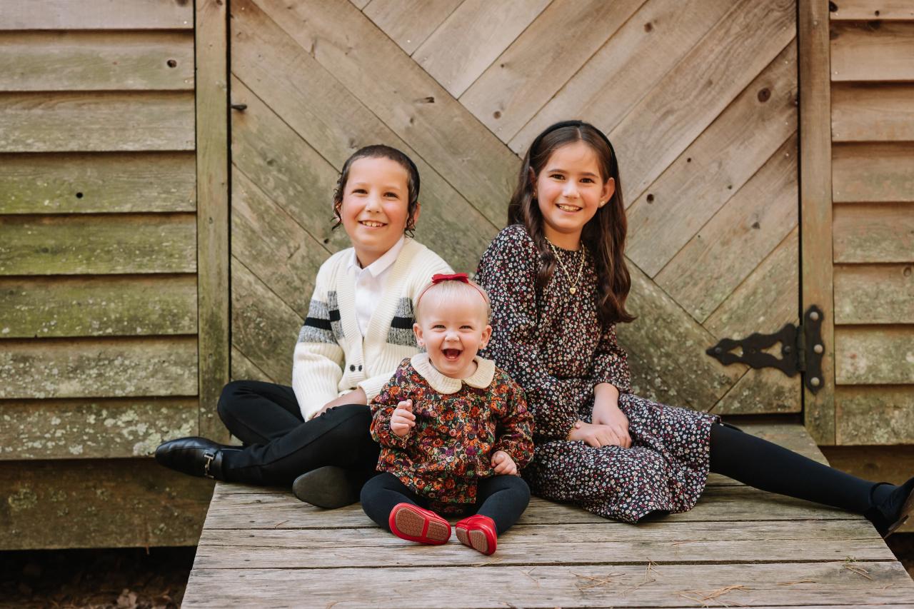 Three siblings sitting together on a wooden porch