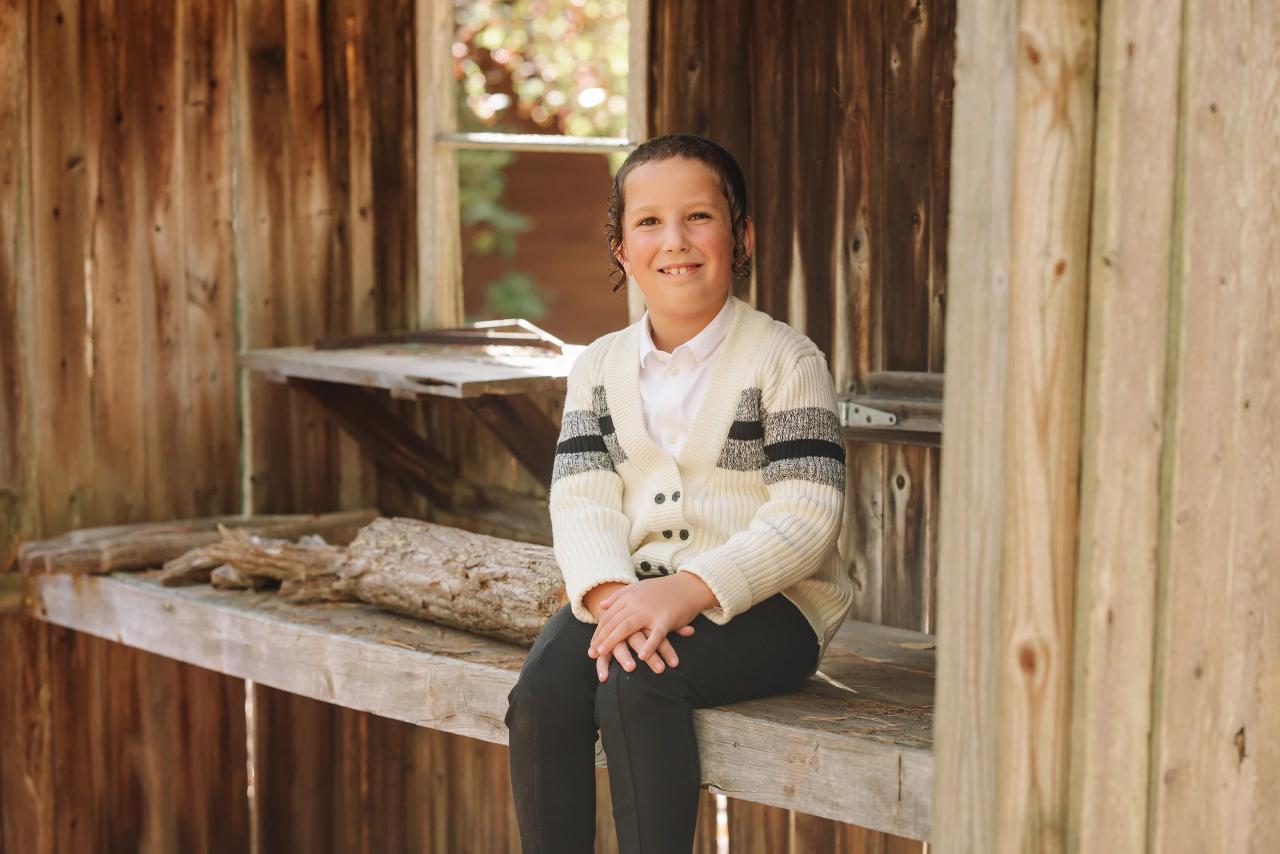 Boy sitting in a rustic cabin window during a family portrait session