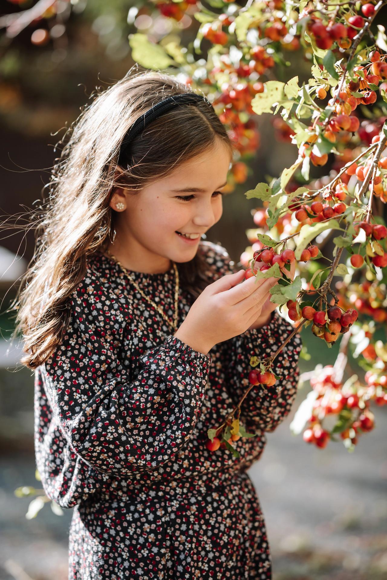 Girl looking closely at autumn leaves outdoors