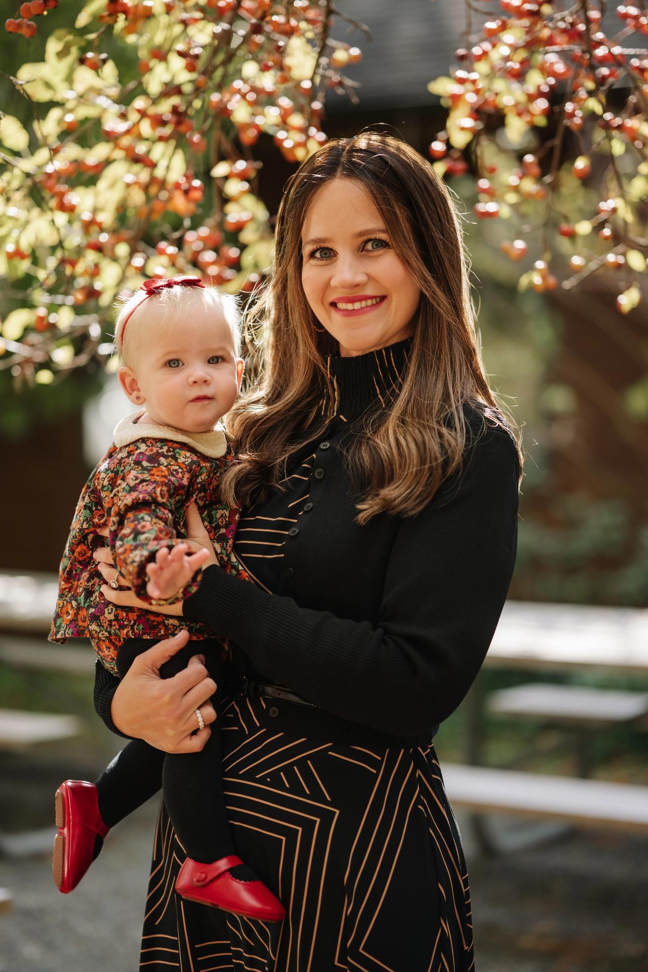 Mother holding her baby beneath autumn foliage