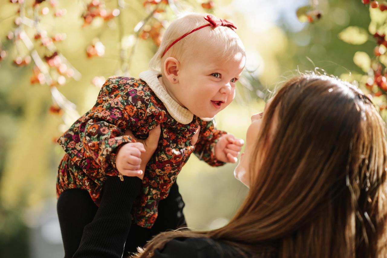 Mother lifting her smiling baby during an outdoor family session
