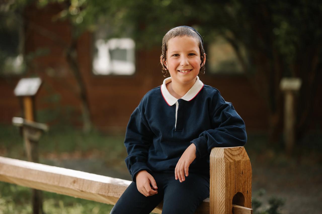 Boy smiling while sitting on a wooden fence