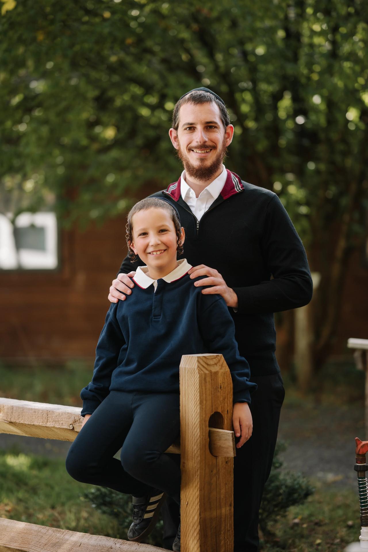 Father standing beside his son on a wooden fence