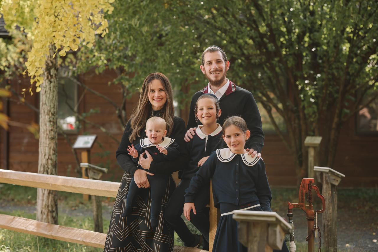 Family of five gathered beside a rustic fence