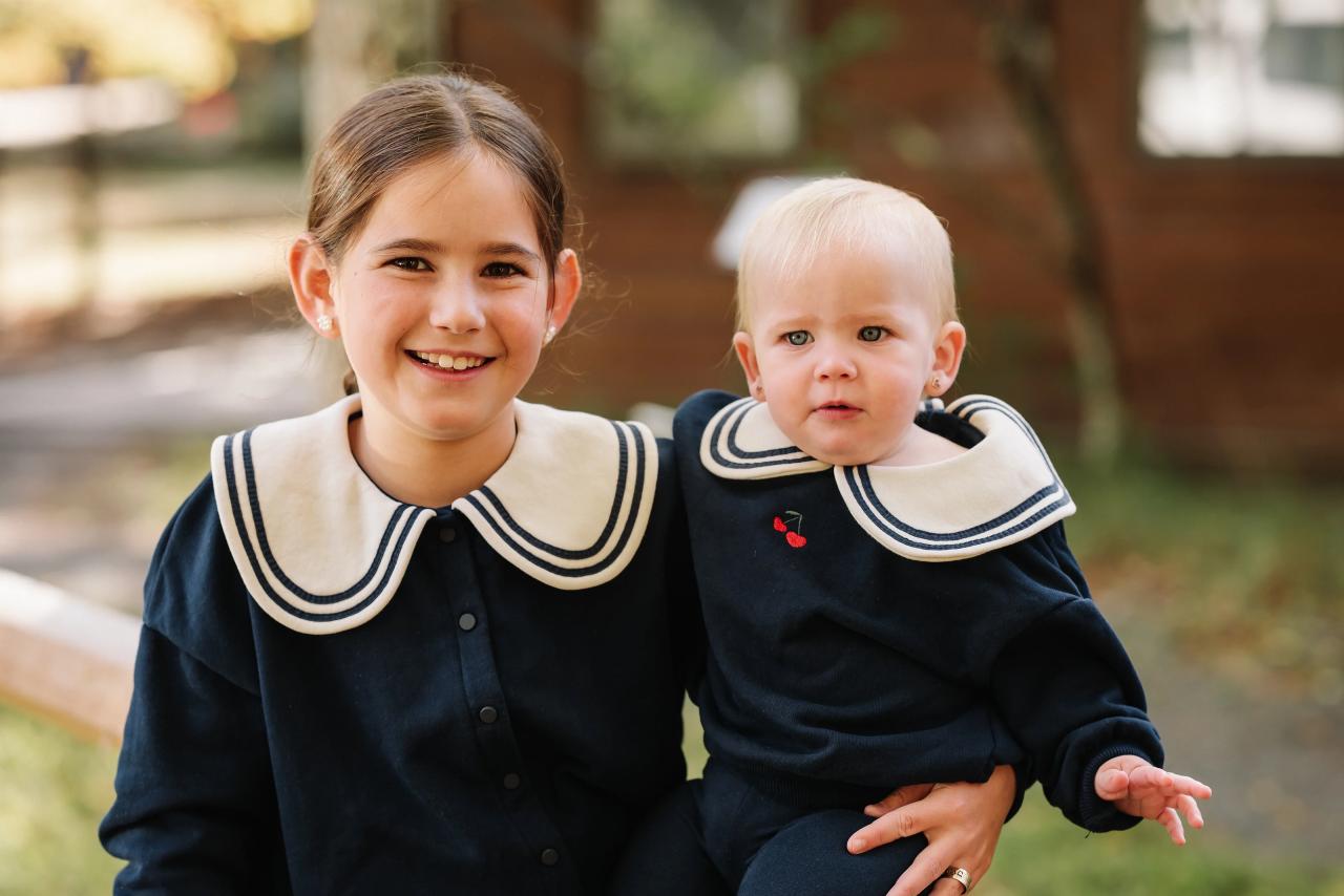 Older sister holding her baby sibling during an outdoor portrait