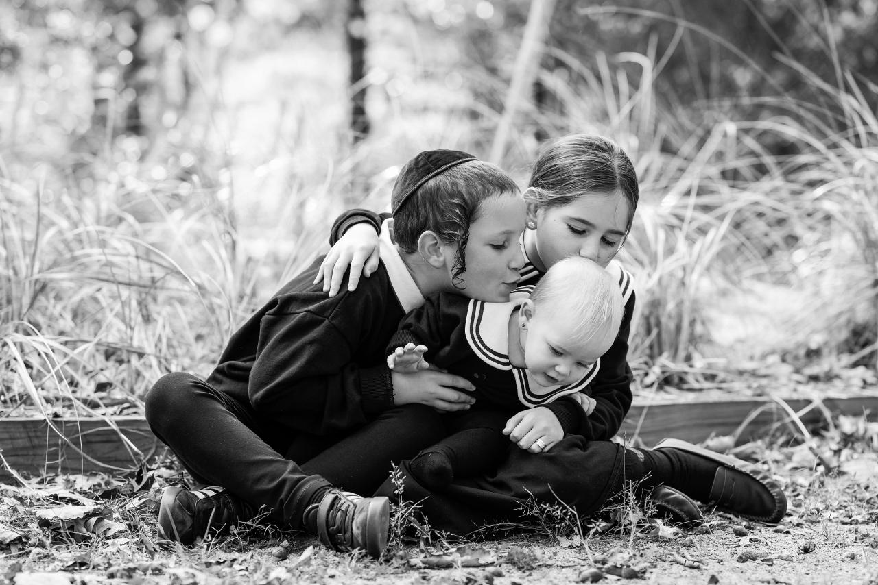 Black-and-white portrait of siblings cuddling their baby sister
